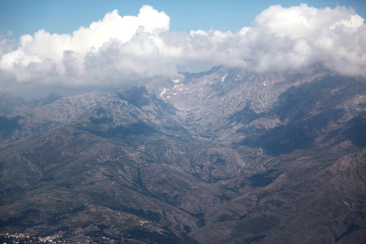 Zoom sur la vallée de l'Erco dominée par Monte Cinto sous les nuages ; le hameau de Lozzi dans le coin gauche